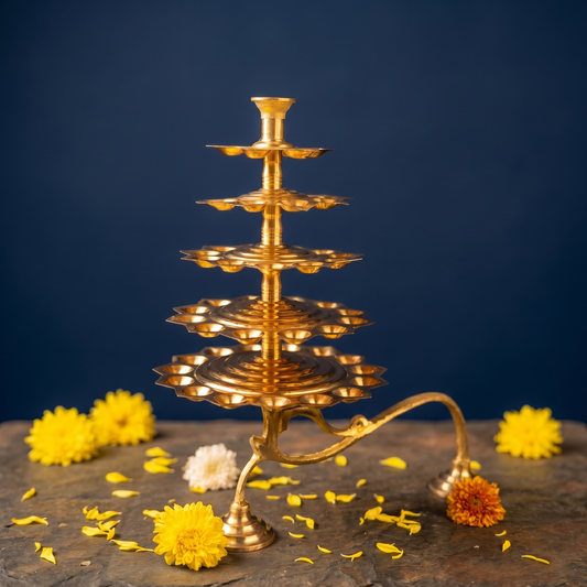 Aal Vilakku Adukku Aarthi with five-tiered layers in a straight front view with yellow and white flowers on a stone surface against a blue backdrop