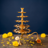 Aal Vilakku Adukku Aarthi with five-tiered layers in a straight front view with yellow and white flowers on a stone surface against a blue backdrop