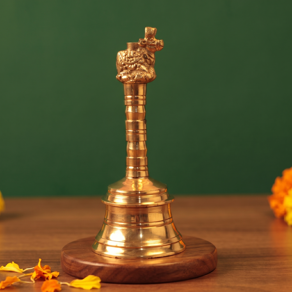 Brass Ghanti Bell Nandhi on the left side angle with Nandhi bull handle and tiered bell base with yellow and orange petals on a wooden plate.