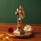 Bala Murugan with Peacock on the right side angle holding vel with red and white flowers and scattered petals on a wooden plate.