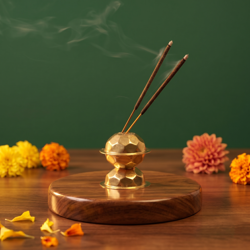 Brass Agarbatti Dhoop Stand in front view with two lit incense sticks releasing smoke with colourful marigolds on a wooden plate.