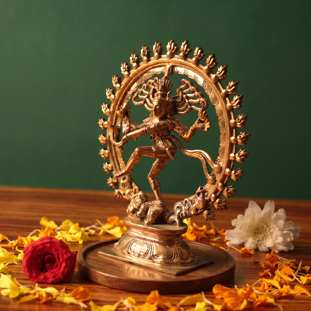 Nataraja idol in right side angle dancing within a fire ring with red and white flowers and scattered petals on a wooden plate.