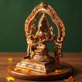 Maariamman idol in right side angle with floral arch prabhavali seated on an engraved base with yellow and orange petals on a wooden plate.