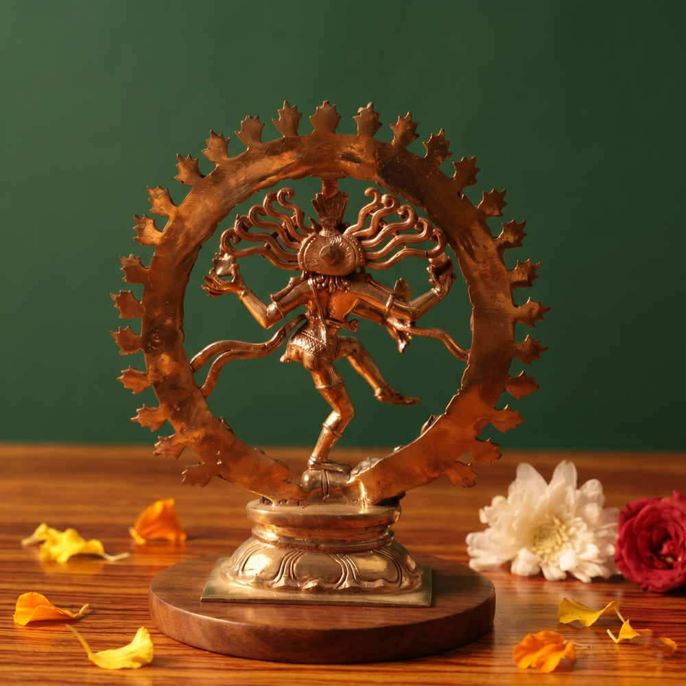 Nataraja idol in back view, dancing within a fire ring on a lotus base with red and white flowers on the left side on a wooden plate.