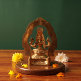 Maariamman idol in back view, with a circular arch prabhavali, seated on a lotus base with yellow and white flowers on a wooden plate.