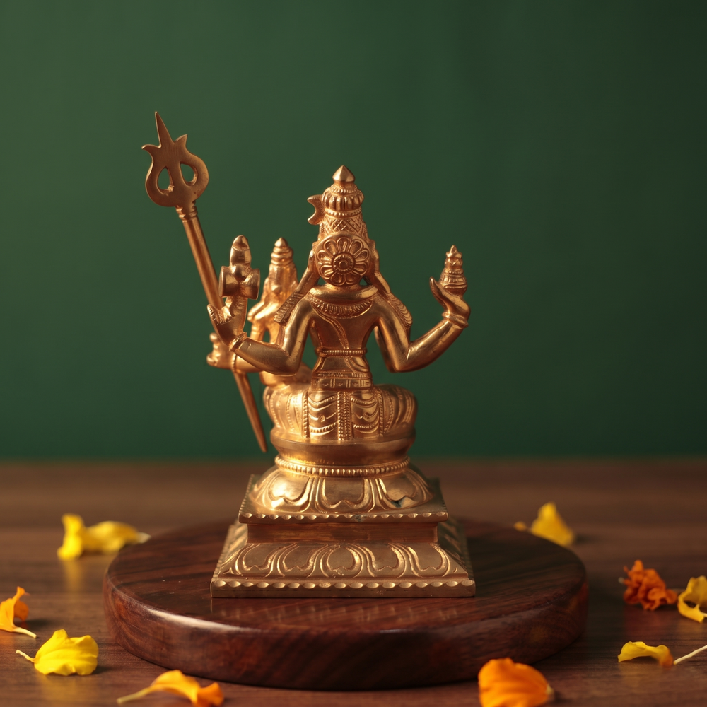 Sorna Aagashabairavar in back view, seated with Parvati holding trishul with yellow and orange petals on a wooden plate.