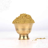 Abishega thirumanjanam powder heaped high in a puja bowl with spilled powder beside shown in slightly low front view against white backdrop.