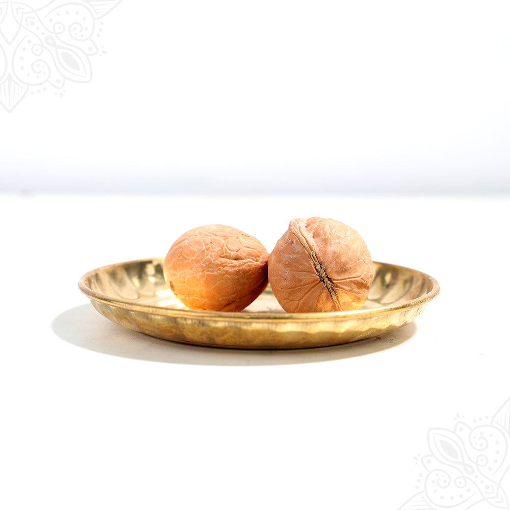 Akhrot whole nuts in straight front facing view placed on a decorative plate showing rough shells for pooja use