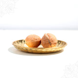 Akhrot whole nuts in straight front facing view placed on a decorative plate showing rough shells for pooja use