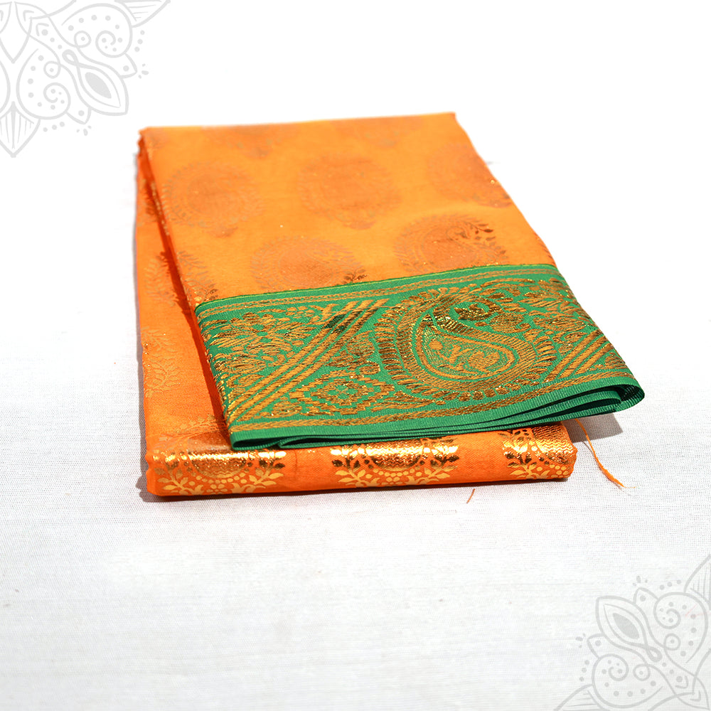 Dark Yellow amman saree with green and gold zari border, folded and placed in a slight right side angle view on a white surface
