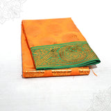 Dark Yellow amman saree with green and gold zari border, folded and placed in a slight right side angle view on a white surface