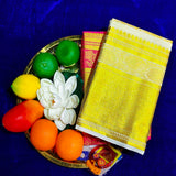 White and rose amman saree with big gold jacquard border placed on pooja plate with fruits and lotus flower top angle view
