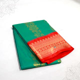 Slight top angle view of dark green amman saree big kota with gold floral print and red zari border on white surface