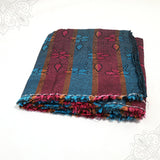 Bedsheet Laila folded in blue and maroon floral stripe pattern with multicolor fringed edge on white surface, slight top-down angle view