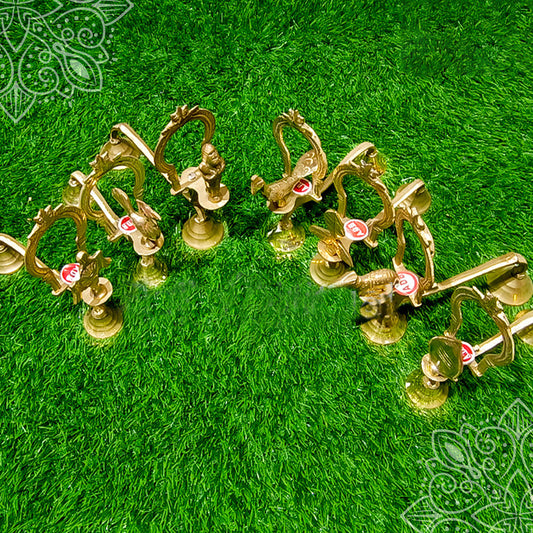 Bomma aarti multiple pieces with deity figure handles displayed in bulk, top angle view on green grass
