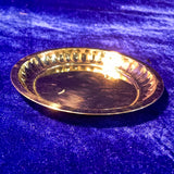 Brass sargam plate with ridged rim, empty pooja plate, side angle view on blue velvet background