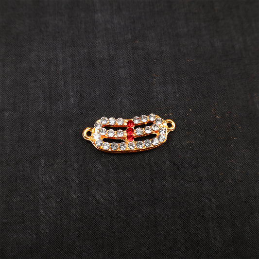 Curved vibhuthi pattai for Sivan with red center stones on dark background slight side angle view for pooja