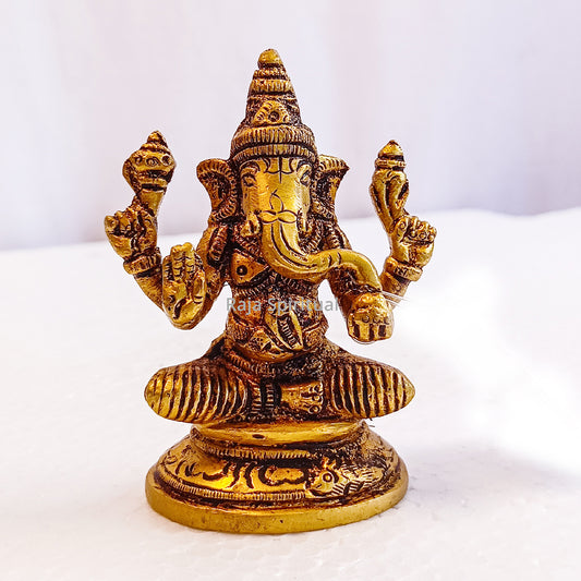 Ganesh idol seated front facing view four hands raised on round pedestal with rat motif