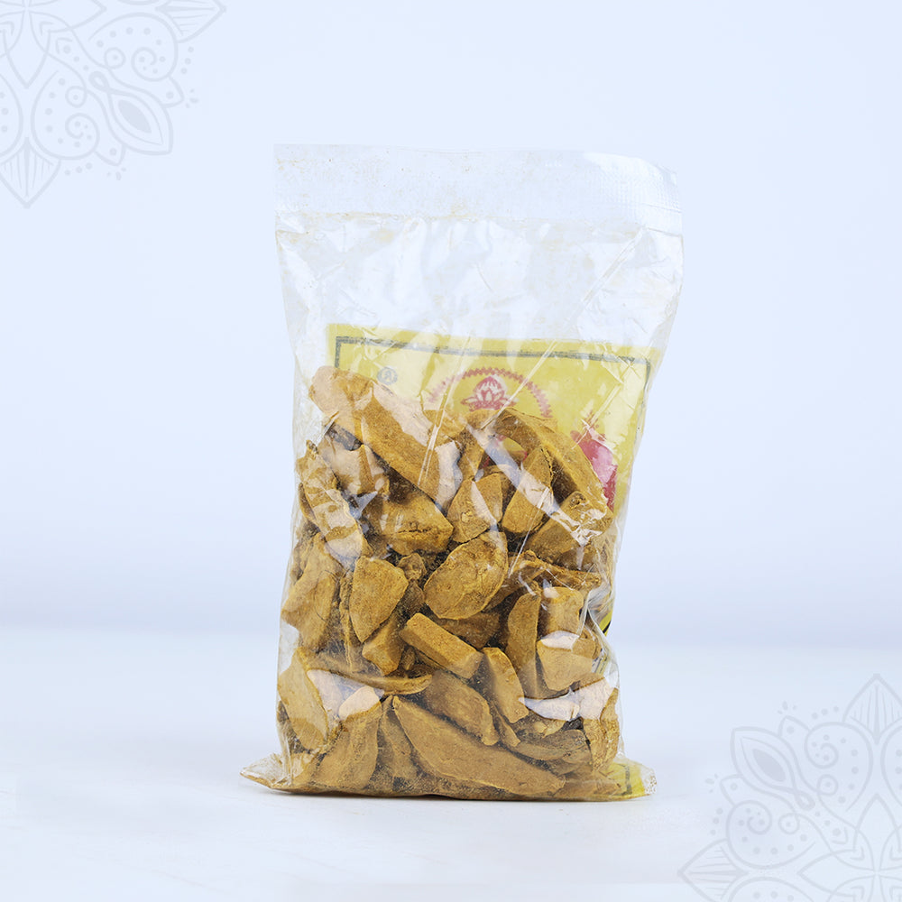 Kasthuri manjal kizhangu dry turmeric pieces in a clear sealed plastic packet shown in straight front view against white backdrop.