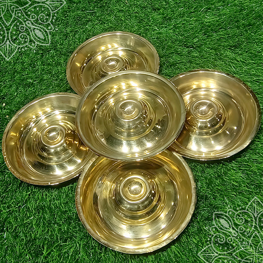 Kumba deepam plates set of five with concentric ring design, arranged in flower pattern, top angle view on green grass
