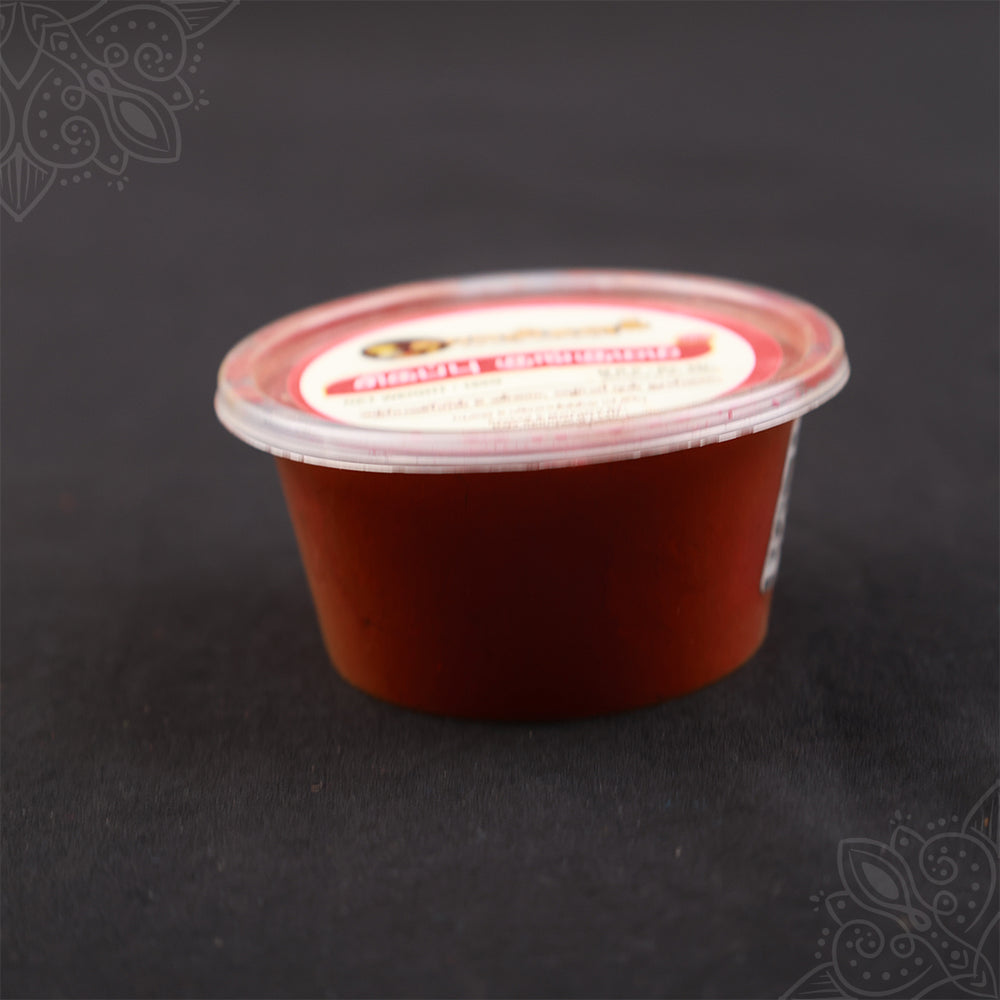 Subamangalam red kumkum pack slight side angle view showing paste texture on dark backdrop