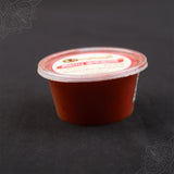 Subamangalam red kumkum pack slight side angle view showing paste texture on dark backdrop