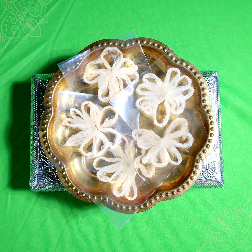 Four thamarai thandu thiri wicks in flower shape placed in urli plate top view for pooja rituals
