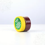 Thazhampoo kumkum box jar lying on side angle view showing yellow lid label for pooja and tilak rituals