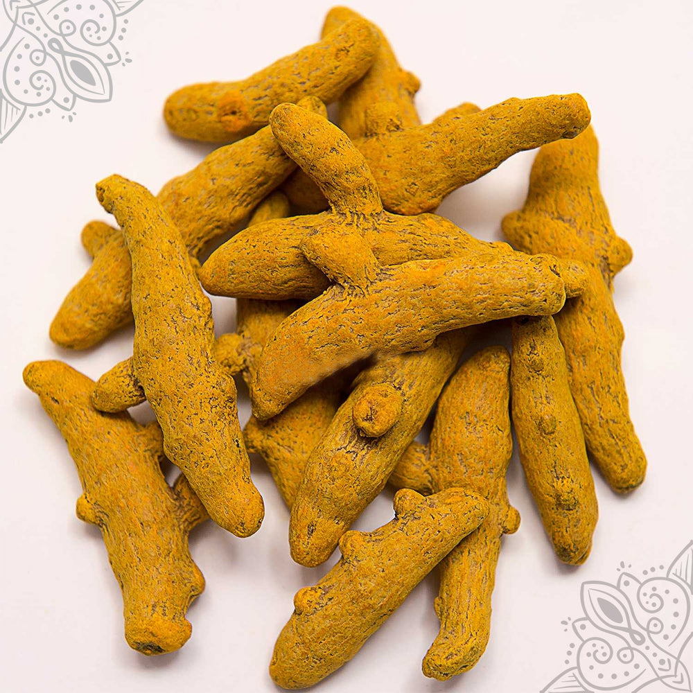 Virali manjal kizhangu whole turmeric fingers piled loose on a white surface showing natural texture, slight top-down view