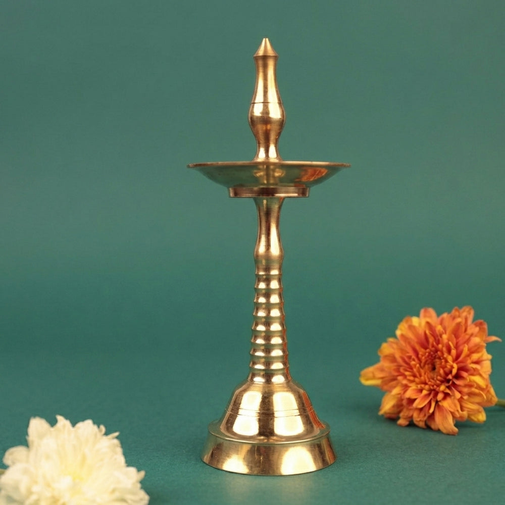 Nilavilakku Kerala floor lamp in straight front view with white and orange chrysanthemum flowers on both sides against a green backdrop