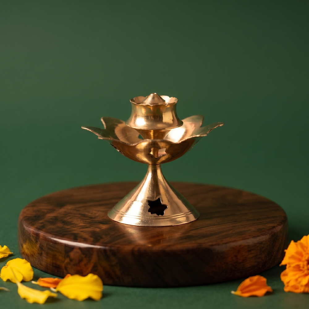 Brass Agarbatti Stand Dhoop Dani Lotus Design with star cutout pedestal and lotus petals with yellow and orange marigolds on a wooden plate.