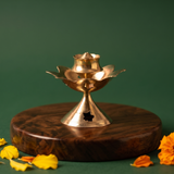 Brass Agarbatti Stand Dhoop Dani Lotus Design with star cutout pedestal and lotus petals with yellow and orange marigolds on a wooden plate.