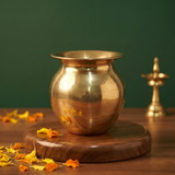 Special Sombu in front view on a wooden base with a small diya and scattered marigold petals against a green backdrop