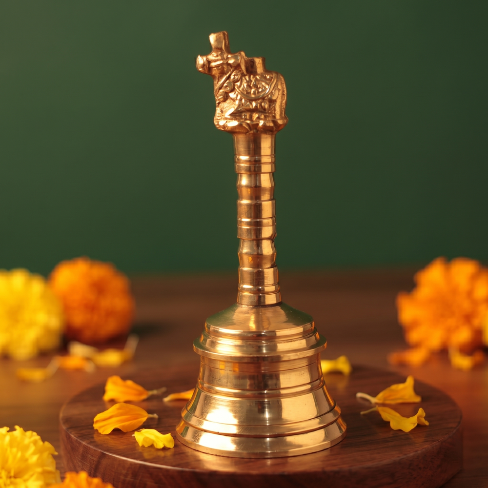 Brass Ghanti Bell Nandhi in right side angle with Nandhi bull handle and tiered bell base with yellow and orange marigolds on a wooden plate.