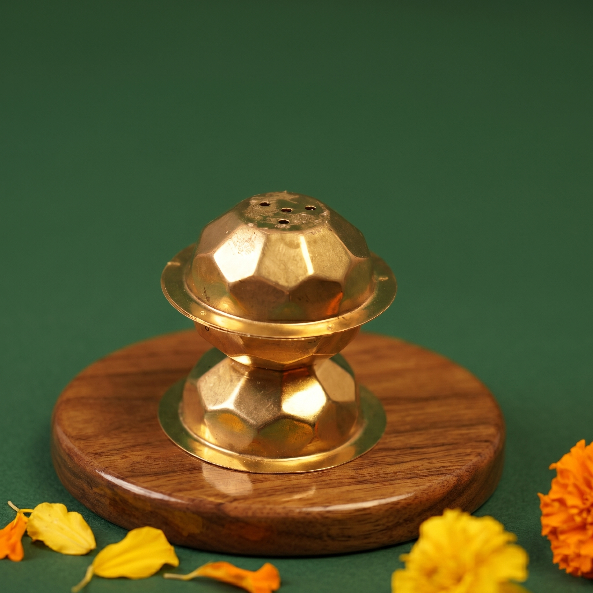 Brass Agarbatti Dhoop Stand in a slight top angle with geometric ball shape and incense holes with yellow and orange marigolds on a wooden plate.