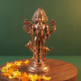 Kala Bhairava idol in front view, holding a trishul, with a dog beside him, on a lotus base with yellow and orange petals, on a wooden plate.