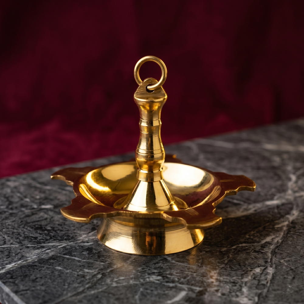 Thookku Vilakku hanging lamp with ring hook and scalloped base in a slight top-angle front view on a marble surface against a maroon backdrop