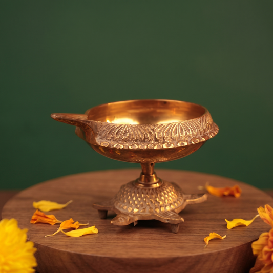 Aamai Vilakku Koorma Deepam with tortoise base in close-up right-side view on a wooden base with petals against a green backdrop