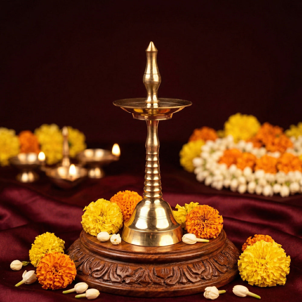 Nilavilakku Kerala floor lamp in a slight top-angle view on a carved wooden base with marigold and jasmine flowers against a maroon backdrop