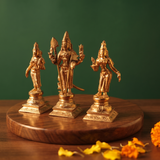 Panchalogam Murugan Set in right side angle with Valli and Devasena on either side, with yellow petals on a wooden plate.