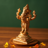 Ganesh Standing Valampuri in right side angle with four arms and ornate detailing with scattered yellow petals on a wooden plate.