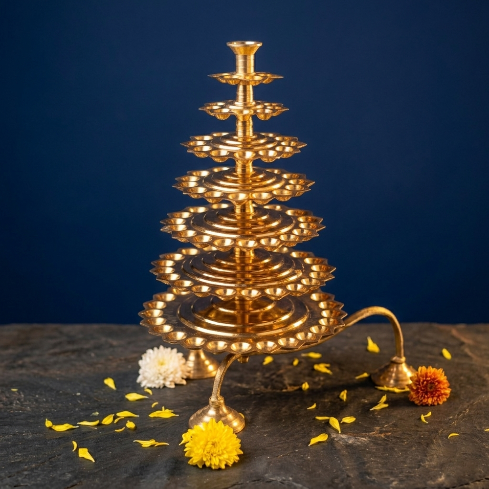 Aal Vilakku Adukku Aarthi with seven tiers in a slight top-angle view with white, yellow, and orange flowers on stone against a blue backdrop