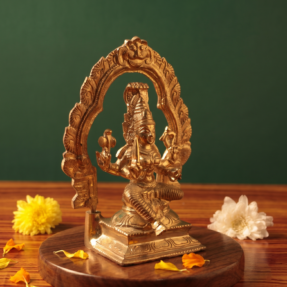 Maariamman idol on the left side angle with leafy arch prabhavali seated on a lotus base with yellow and white flowers on a wooden plate.