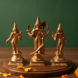 Panchalogam Murugan Set in back view with Valli and Devasena on either side, with a peacock at the base with yellow petals on a wooden plate.