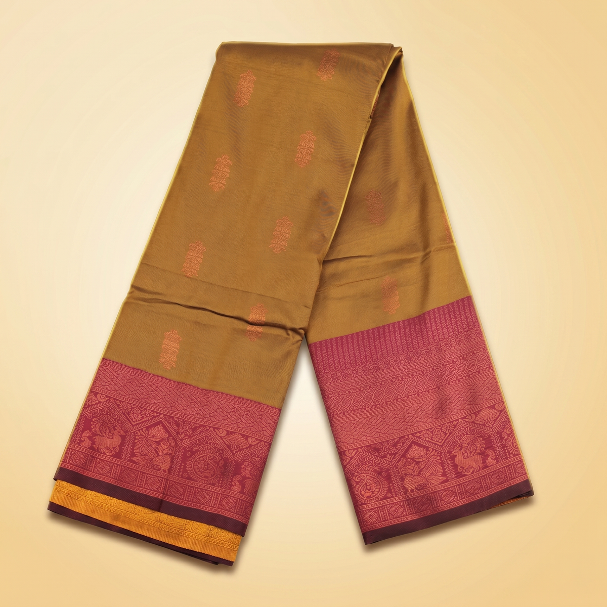 Amman Soft Silk Saree in olive gold folded straight with maroon 8 inch border and small leaf motifs on cloth
