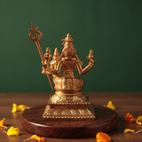 Sorna Aagashabairavar in back view, seated with Parvati holding trishul with yellow and orange petals on a wooden plate.