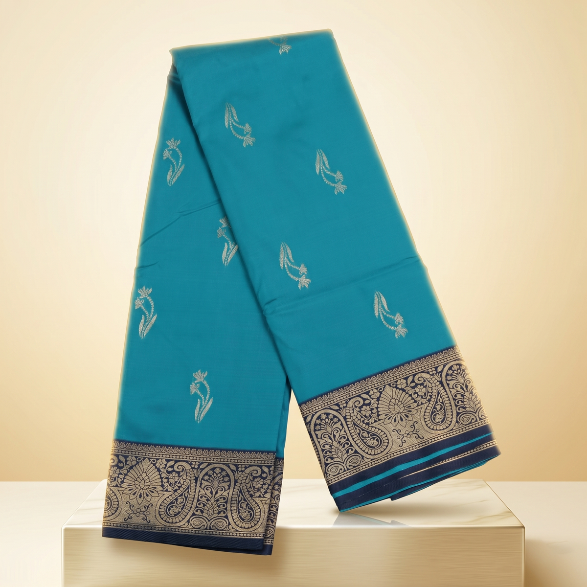 Amman soft silk saree flower design 4 inch border in peacock blue with navy paisley border, placed on marble straight front view.