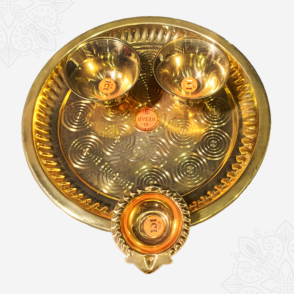 Aarti plate with two bowls and a diya shown in top-down view with circular engraved design against white backdrop.