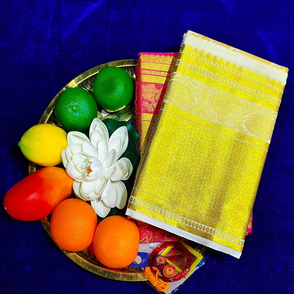White and rose amman saree with big gold jacquard border placed on pooja plate with fruits and lotus flower top angle view