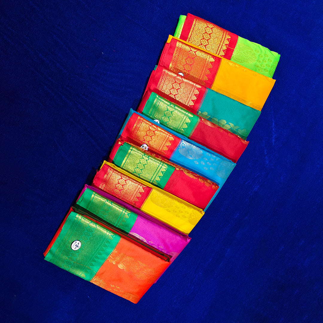 Top view of multiple amman saree big kota folded in assorted bright colors with gold zari border on blue surface
